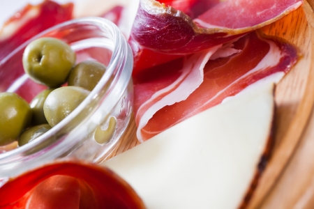 A big piece of curled bacon served with cheese and olives.の写真素材