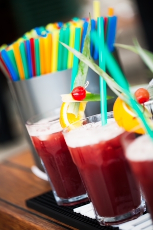 Big glasses filled with red cranberry juice and different colour straws.の写真素材