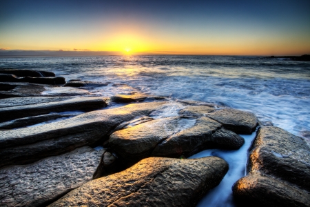 overlooking the horizon on a rocky shore in the magical hour of sunriseの写真素材