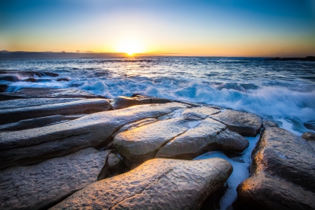 the breaking dawn over a rocky shore and lively seaの写真素材