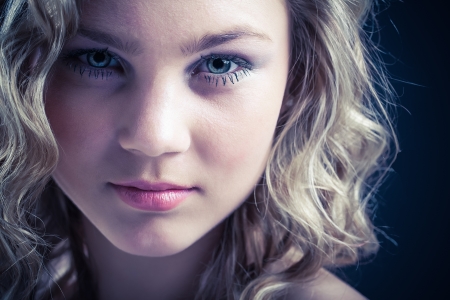 a close-up  of a beautiful young caucasion girl with blond curly hair and big bright eyes shot with a wet chrome texture to the photographの写真素材