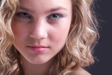 a close-up of a beautiful young caucasion girls face with blond curly hair and soft pinks lipsの写真素材