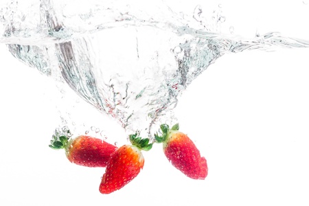 three strawberries being cast into fresh waterの写真素材