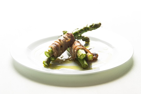 asparagus wrapped in threes in spiced bacon and placed delicatly on a whitel porcelyn plateの写真素材