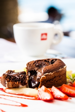 a steamy lava cake broken open served with fresh fruit and coffeeの写真素材