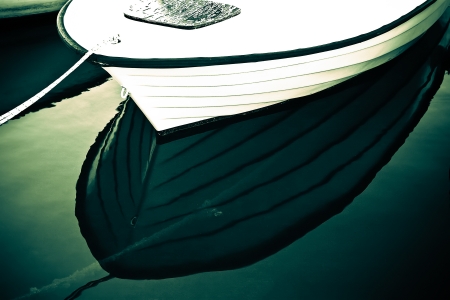a white dinghy boat docked with a symmetric reflection in the still waterの写真素材