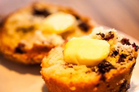 a delicious blueberry muffin sliced in half with butter melting on topの写真素材