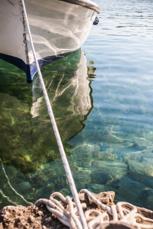 a cropped image of a tiny white and blue row boat docked to a rockの写真素材