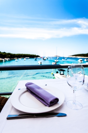 a close-up on a restaurant table with a purple textured napkin overlooking the pierの写真素材
