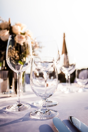 three crystal glasses on a decorative table  with roses and church tower in the backgroundの写真素材