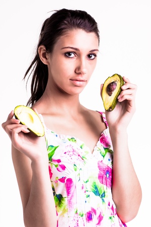 pretty caucasian brunette girl holding up cut avocado in her handsの写真素材