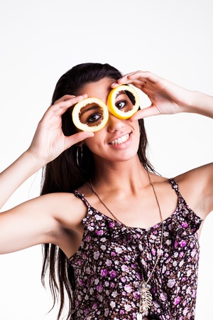 pretty caucasian brunette girl holding hollow lemon peels infront of her eyes smilingの写真素材