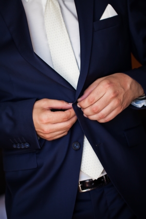 a groom wearing a tailored navy suit buttoning upの写真素材