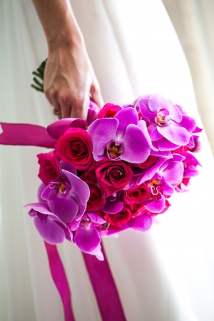 cropped image of a bride holding her pink and magenta bouquet upside down tied together in bright pink ribbonの写真素材