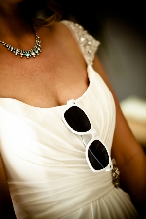 cropped image of a bride on her wedding day with white sunglasses tucked into the front of her wedding dressの写真素材