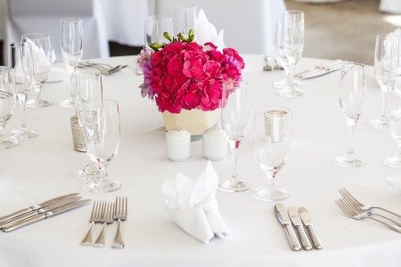 trio of pink and purple flowers as the centerpiece of a crisp and clean set tableの写真素材