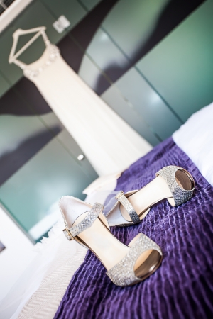 image of the brides bling shoes on the purple blanket with her wedding dress in the backgroundの写真素材