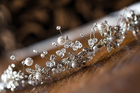 a close-up image of a handmade crystal and pearl tiara resting on a wooden tableの写真素材