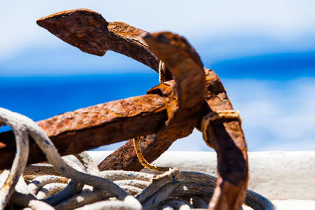 close-up image of a rustic anchor resting on the harbor floor with old rope surrounding itの写真素材