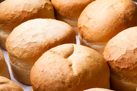 a close-up of a batch of round white bread loafs cooling off on a counter