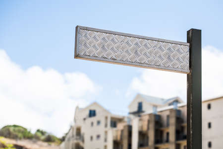 an image of a textured steel street sign with apartment buildings standing in the background