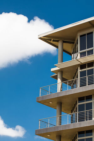 an image of a cropped tall storey buildings balconies with a bright blue sky in the backgroundの写真素材