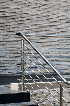 an image of steel railings following along the passage and steps with a gray stone wall in the backgroundの写真素材