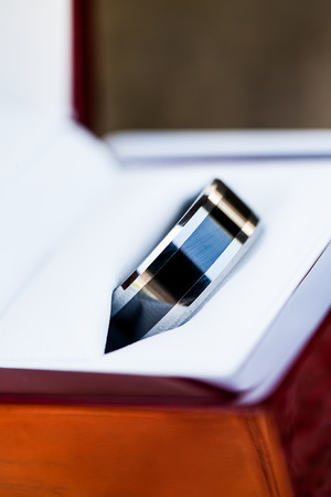 a close-up image of the grooms black and silver wedding ring in a white leather and wooden casingの写真素材