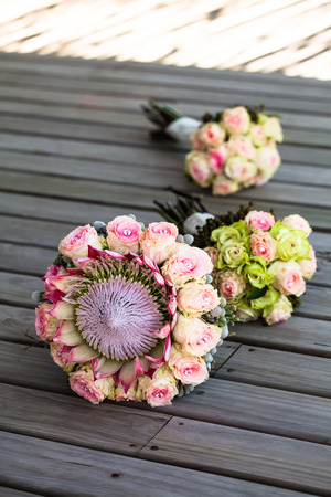 image of the bride and her bridesmaids bouquets lying on the wooden deck in the shade in a rowの写真素材