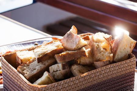 freshly cut homemade bread in a basktet on a table with the sun shining on itの写真素材