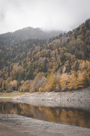 Lake Kruth-Wildestein in Vosges with low waterlevel and autumnal trees on mountains. dark moody skiesの写真素材