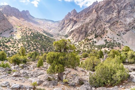 The beautiful mountain trekking road with clear blue sky and rocky hills and the view of Alaudin lake in Fann mountains in Tajikistanの写真素材