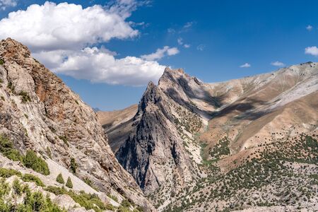 The beautiful mountain trekking road with clear blue sky and rocky hills and the view of Alaudin lake in Fann mountains in Tajikistanの写真素材