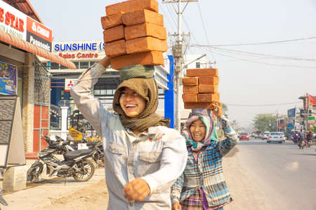 Mandalay/Myanmar-05.03.2017:Women walking on the street and carry on their head stack of bricksのeditorial素材