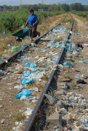 Durres, ALBANIA, August 03, 2009: Deep sadness at seeing so much garbage in a beautiful natural place near the sea. Woman crosses the railway.のeditorial素材