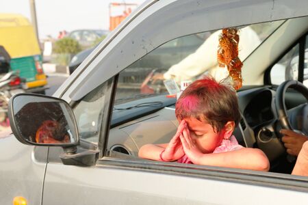 NEW DELHI, DELHI / INDIA â September 15 2016: A little girl is folding her hands while praying to Hindu god Ganesh through a car window on the occasion of Ganesh Visarjan, New Delhi, India.のeditorial素材