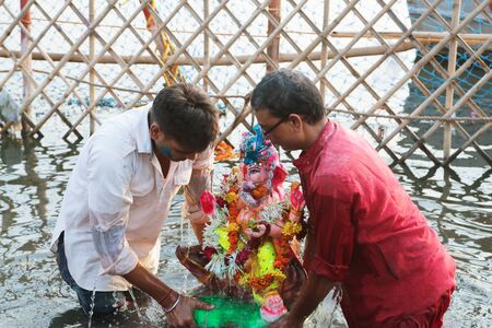 NEW DELHI, DELHI / INDIA â September 15 2016: Two devotees are immersing an Idol of Hindu god Ganesh in Yamuna river, New Delhi, India.のeditorial素材