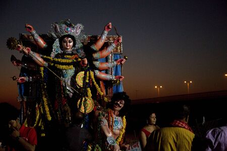 New Delhi / India â September 30 2017: An Idol of Hindu Goddess Durga with eight arms depicting a fighting scene between Goddess Durga and a Devil. Is rested among the crowd of unidentified people on the Yamuna River on the evening of Vijay Dashami in Nのeditorial素材