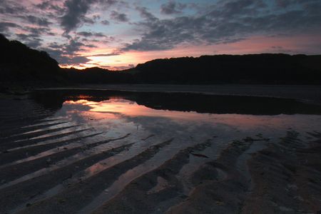 the sunrise reflecting off of the ripples in the sand of the river Erme in South Hams area of Devonの写真素材