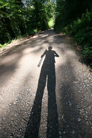 A low sun elongates the photographers shadow on a woodland track in Devonshire UKの写真素材