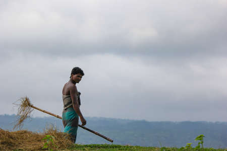 Sunamganj, Bangladesh-May 17,2015: A young farmer holding bamboo pole in hand wearing traditional...