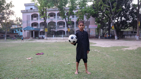 Natore, Bangladesh- March 02, 2021: A Muslim boy holding football before start of game in front of School in villageのeditorial素材