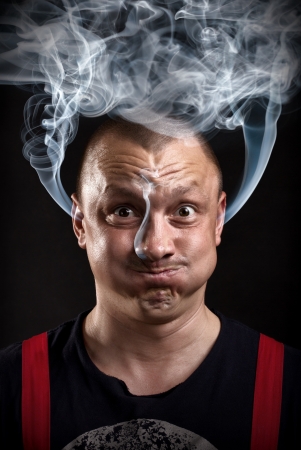 Stressed man with waving smoke from earsの写真素材
