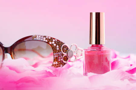 Pink nail polish with rose petals and glassesの写真素材