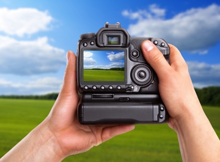 Hands holding digital camera and capturing rural landscapeの写真素材