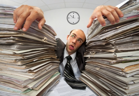 Exhausted businessman has had too much of his paperworkの写真素材