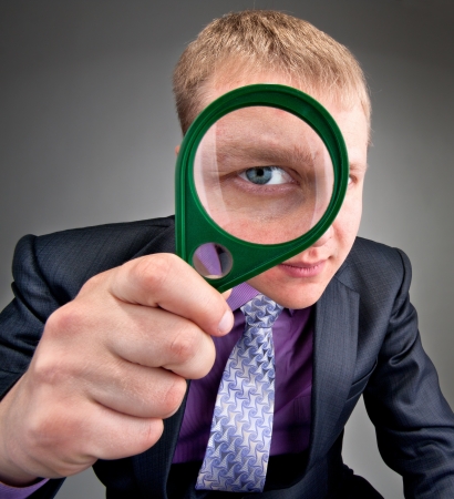 Worried businessman looking to you through magnifier lensの写真素材