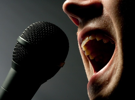 Close-up of man singing to microphone in darkの写真素材