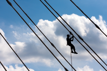Silhouette of construction climber against blue skyの写真素材