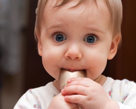Portrait of shy baby girl holding spoon in mouthの写真素材